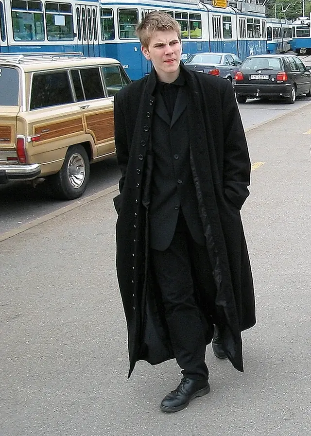 Hendrik im Jahr 2003: schwarzer Anzug und langer Mantel vor einer Straßenbahn.